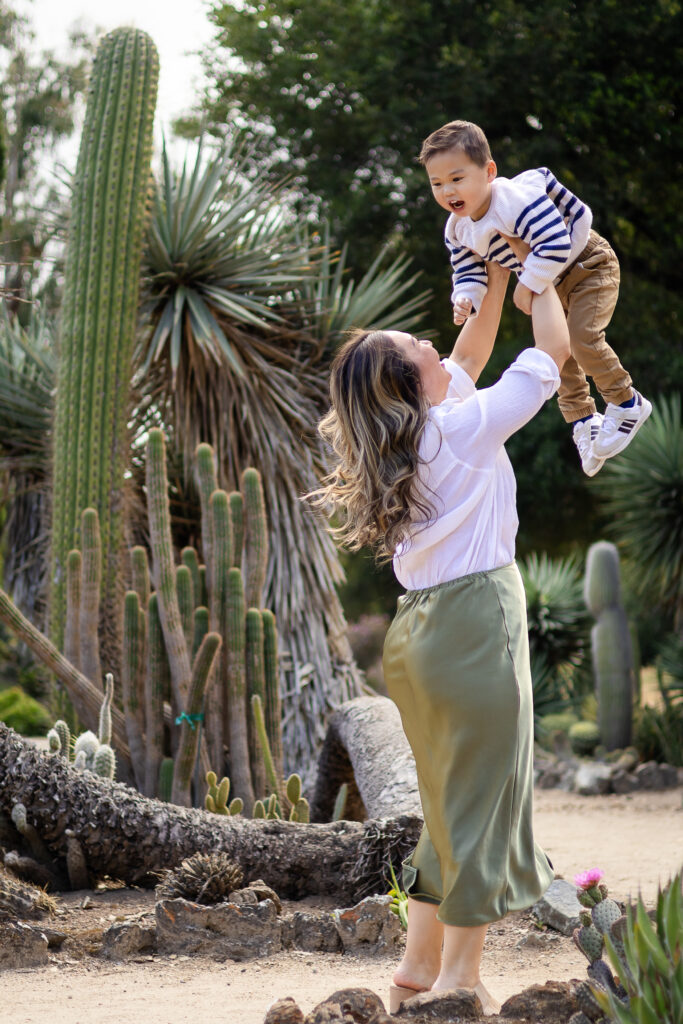 Mom lifting her son in the air surrounded by towering cacti during their Arizona Cactus Garden family photoshoot.