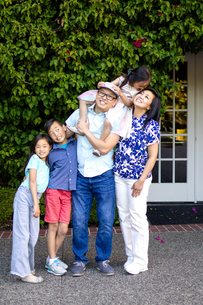 Family of five laughing together outside with playful poses at Kohl Mansion Burlingame