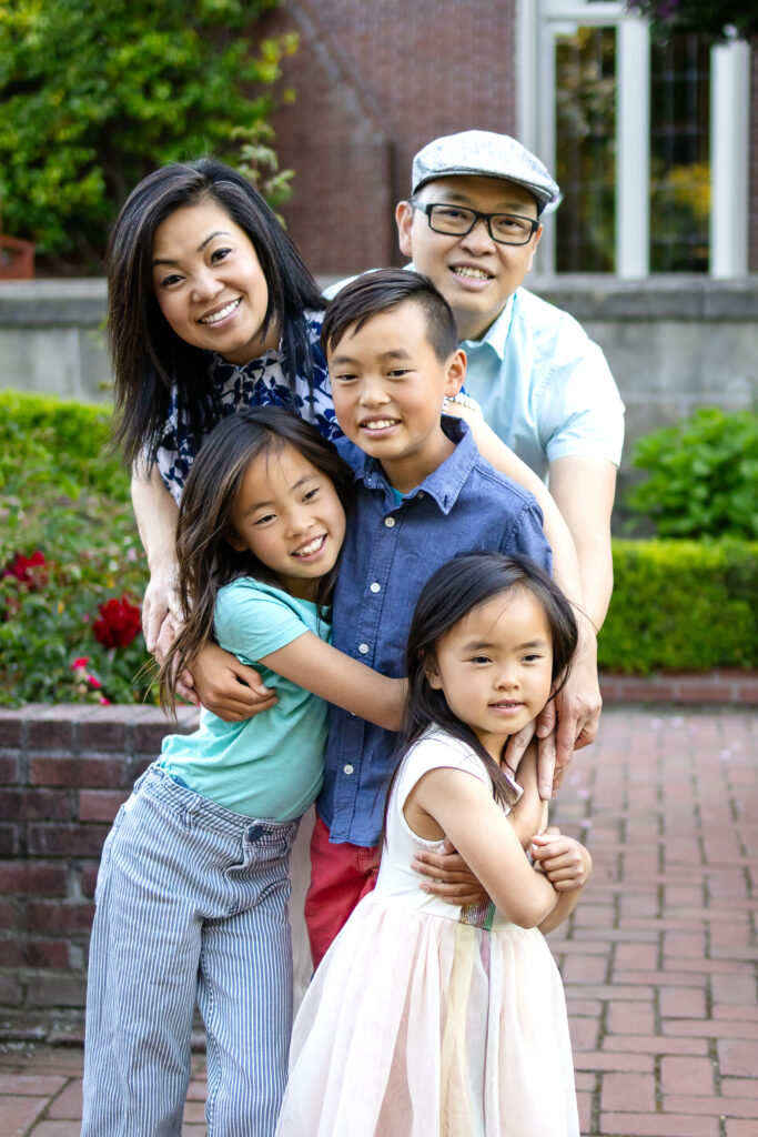 Family of five playfully stacked in height order, with siblings smiling and dressed in soft pastels at Kohl Mansion Burlingame