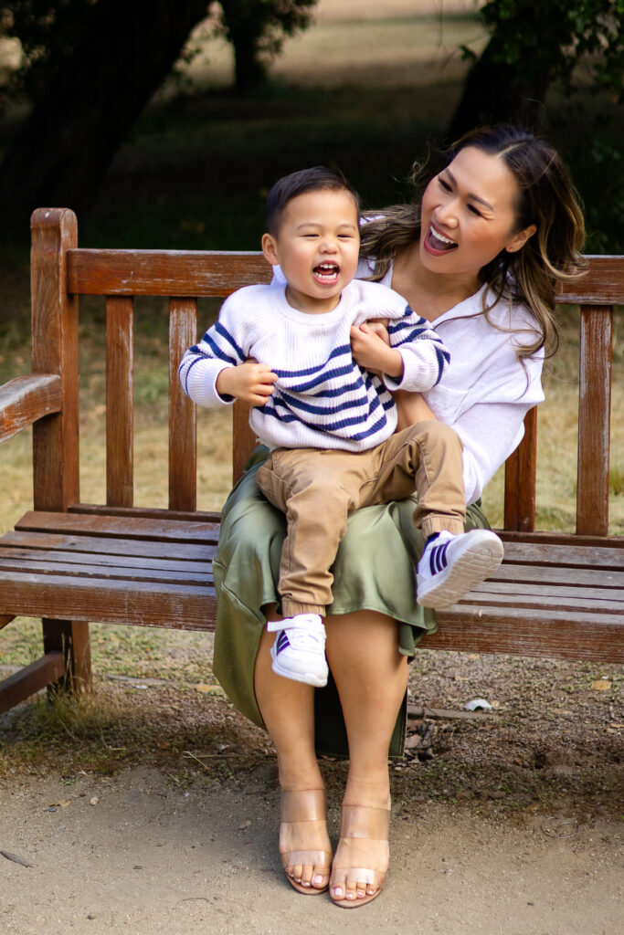 Mom and son laughing together on a wooden bench during a lifestyle family session at the Arizona Cactus Garden
