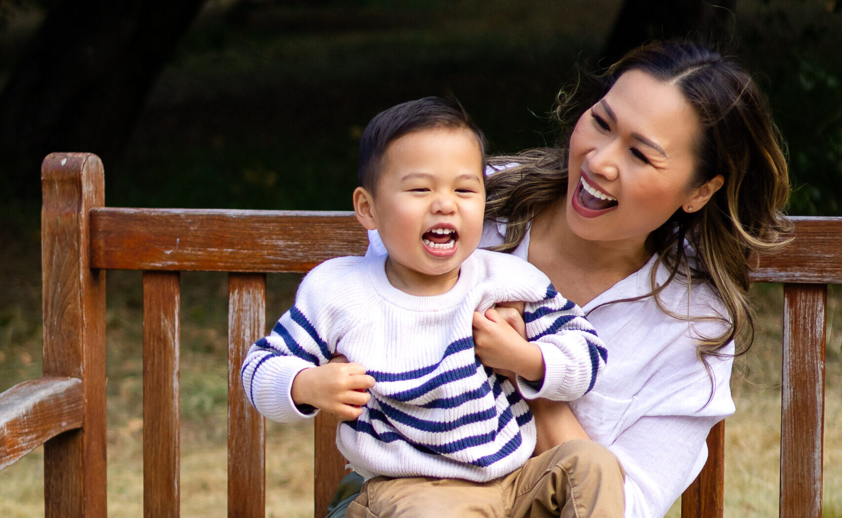 Mom and son laughing together on a wooden bench during a lifestyle family session at the Arizona Cactus Garden