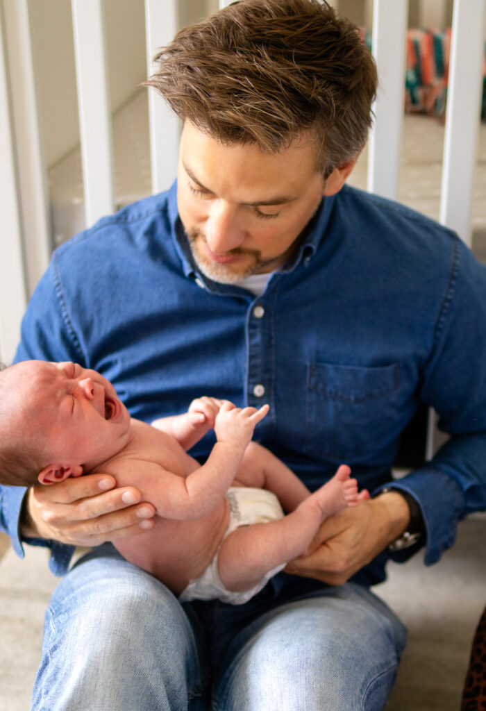 Candid moment of dad comforting his newborn during an in-home session by a San Francisco newborn photographer.