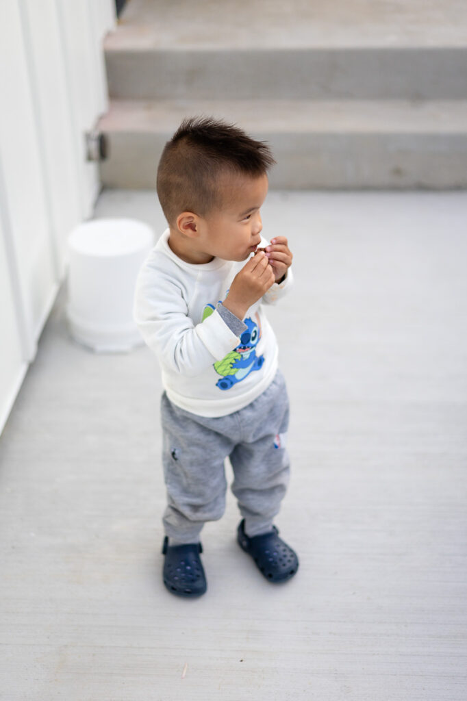 Side profile of toddler enjoying a snack on porch steps – Tips for Family Photos with Toddlers - ellobelle photography