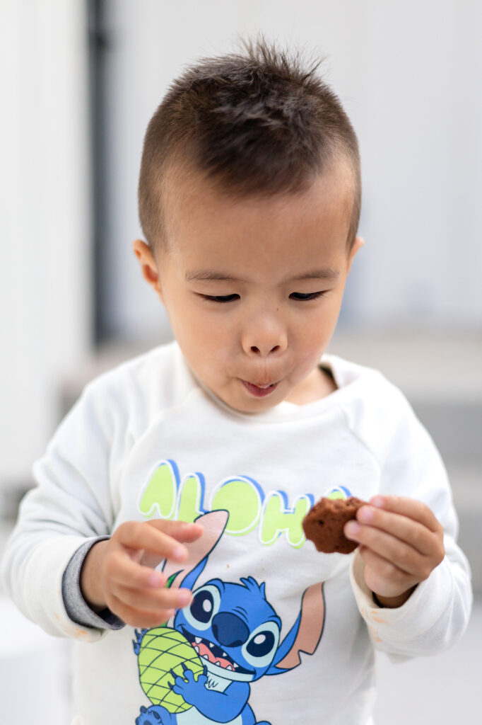 Close-up of toddler making a funny face while holding cookie – Tips for Family Photos with Toddlers - ellobelle photography