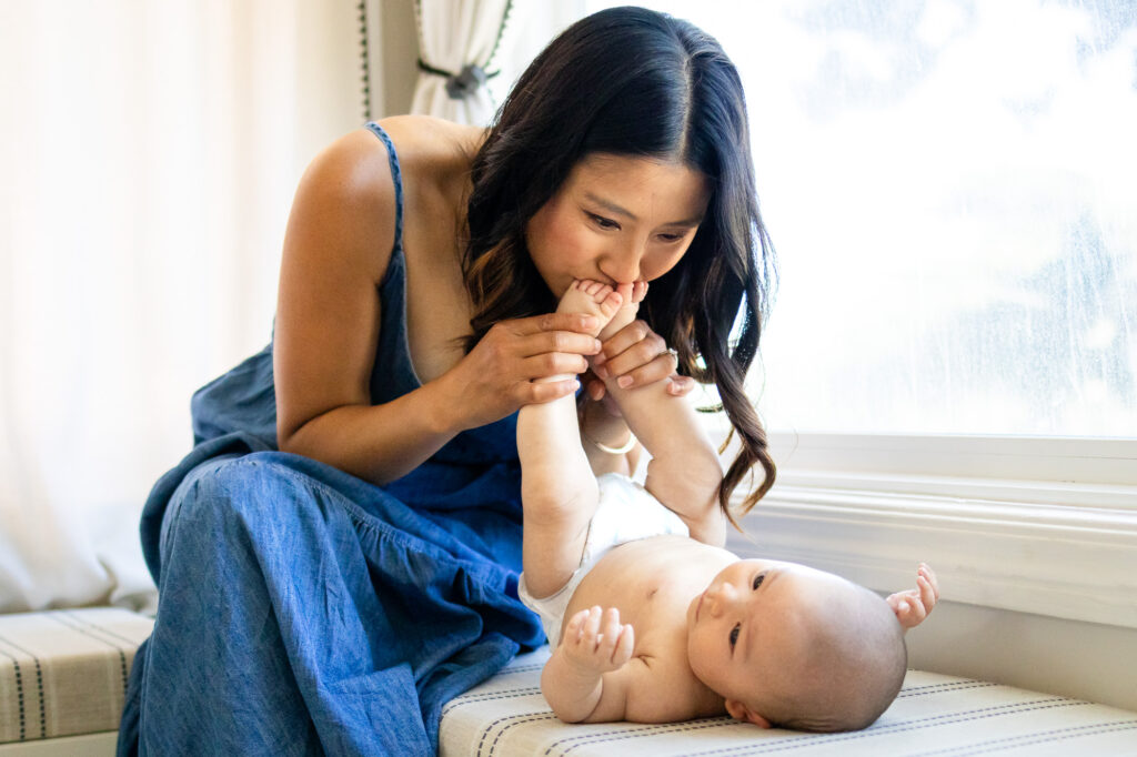 Tender moment of a mom kissing her baby’s tiny toes during an in-home newborn session