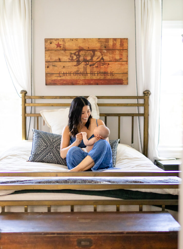 Mother and baby sitting comfortably on a bed, sharing a sweet moment in natural light