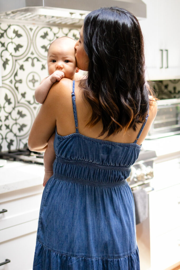 Mom kissing baby’s head while baby looks over her shoulder for a natural timing for newborn photography guide