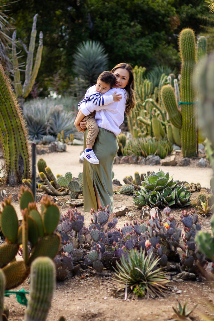 Candid moment of mom lifting her child among towering succulents at the arizona cactus garden.