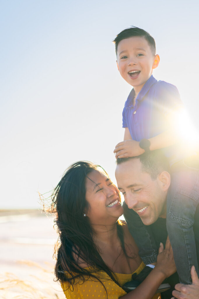 Smiling parents lift their son on their shoulders during golden hour at Alviso Marina County Park – captured by Ellobelle Photography