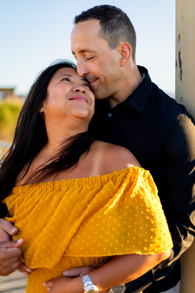 Couple embraces with a soft kiss and loving smiles during golden hour at Alviso Marina County Park – Ellobelle Photography