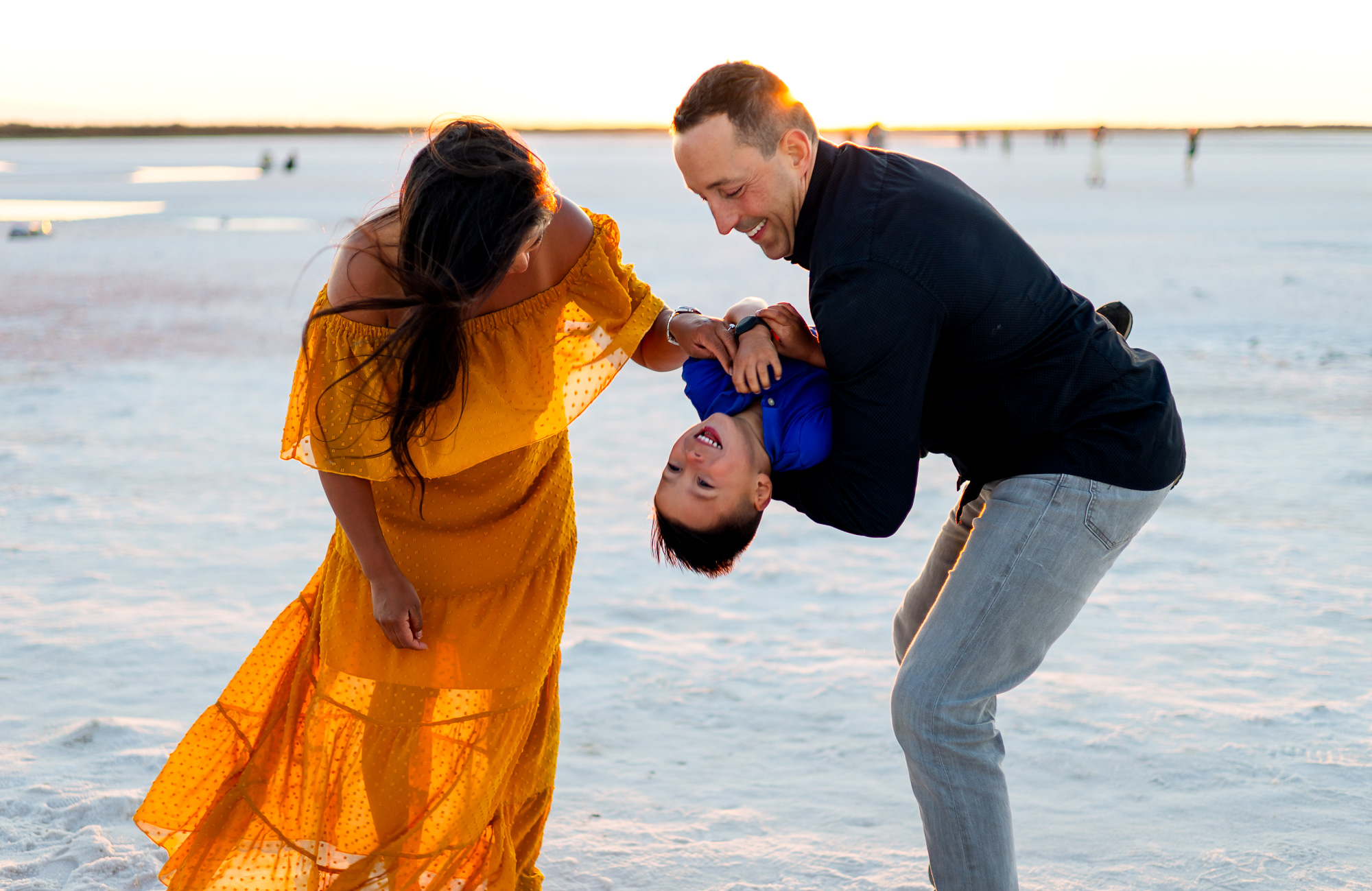 Mom and dad playfully hold their son upside down while laughing at Alviso Marina County Park – Ellobelle Photography
