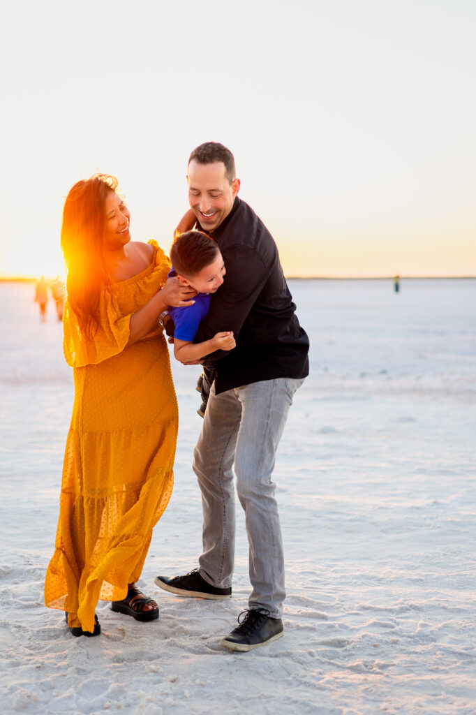 Family laughs together while playing and hugging in golden light at Alviso Marina County Park – Ellobelle Photography