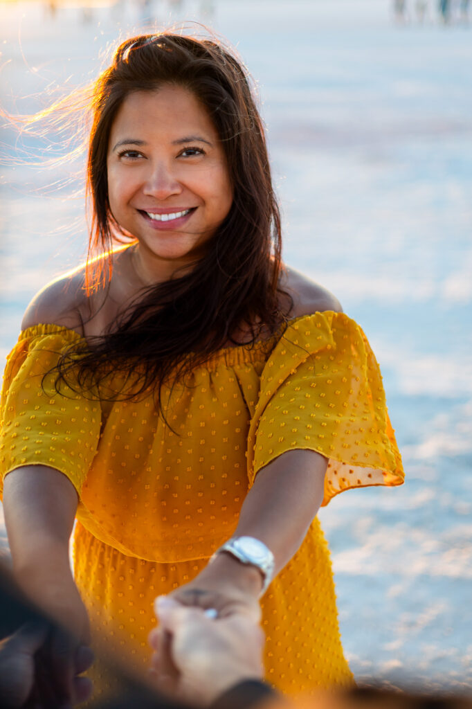 Smiling woman in yellow dress reaches forward while bathed in golden light at Alviso Marina County Park – Ellobelle Photography