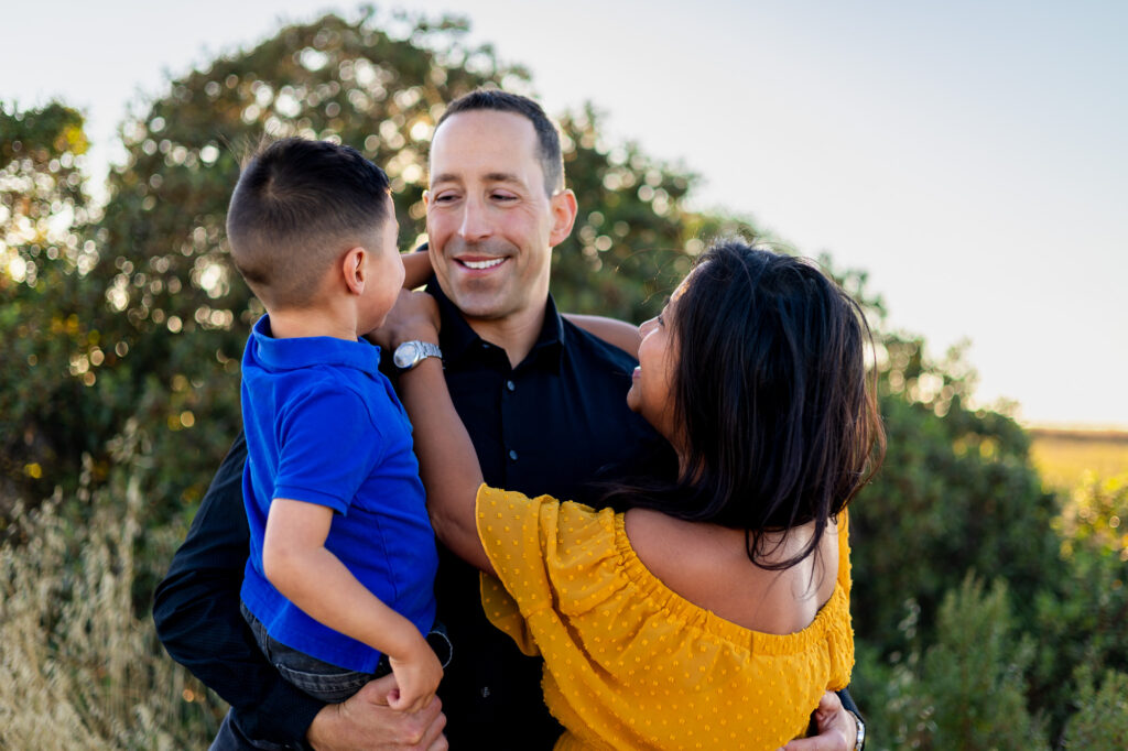 Parents lovingly smile at their son while holding him close at Alviso Marina County Park – Ellobelle Photography
