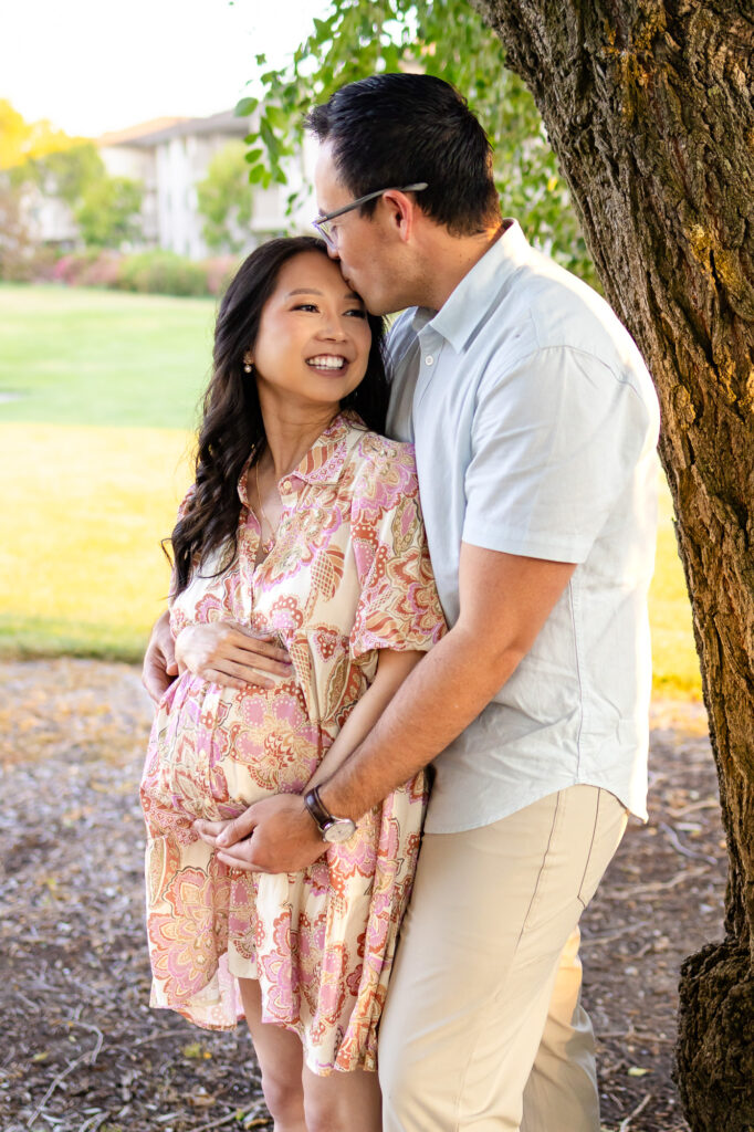 Maternity Photography Poses – ellobelle photography: Partner kisses forehead while holding baby bump under tree during golden hour