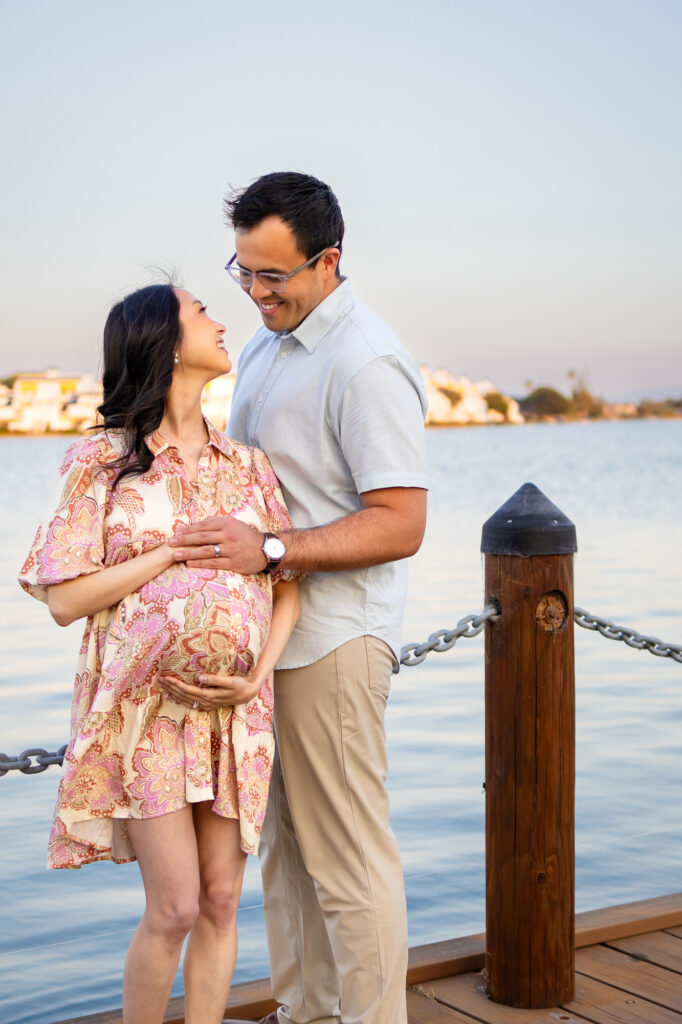 Maternity Photography Poses - ellobelle photography: Mom rests her head on partner’s chest while holding baby bump on a dock