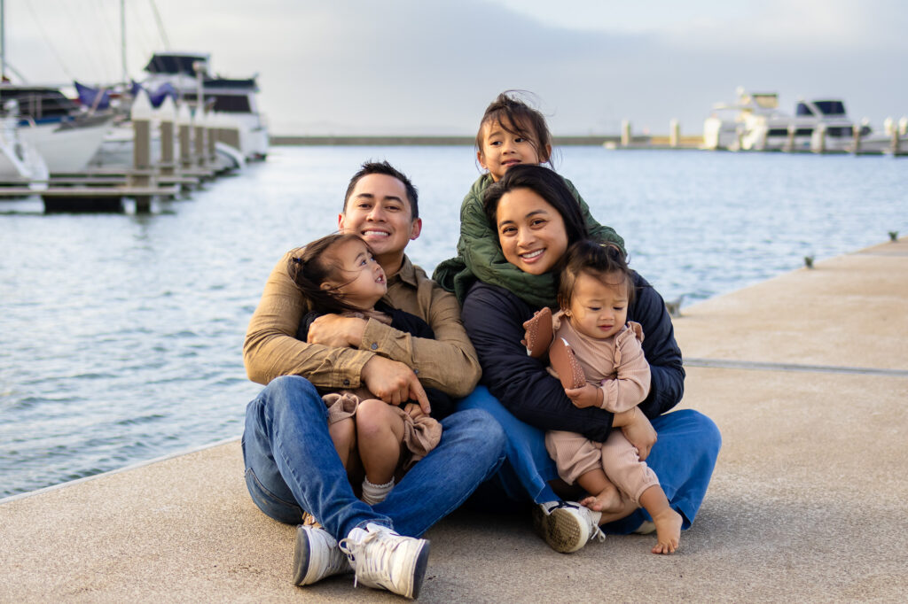 Family cuddling on a boat dock with Bay views at Oyster Point Park