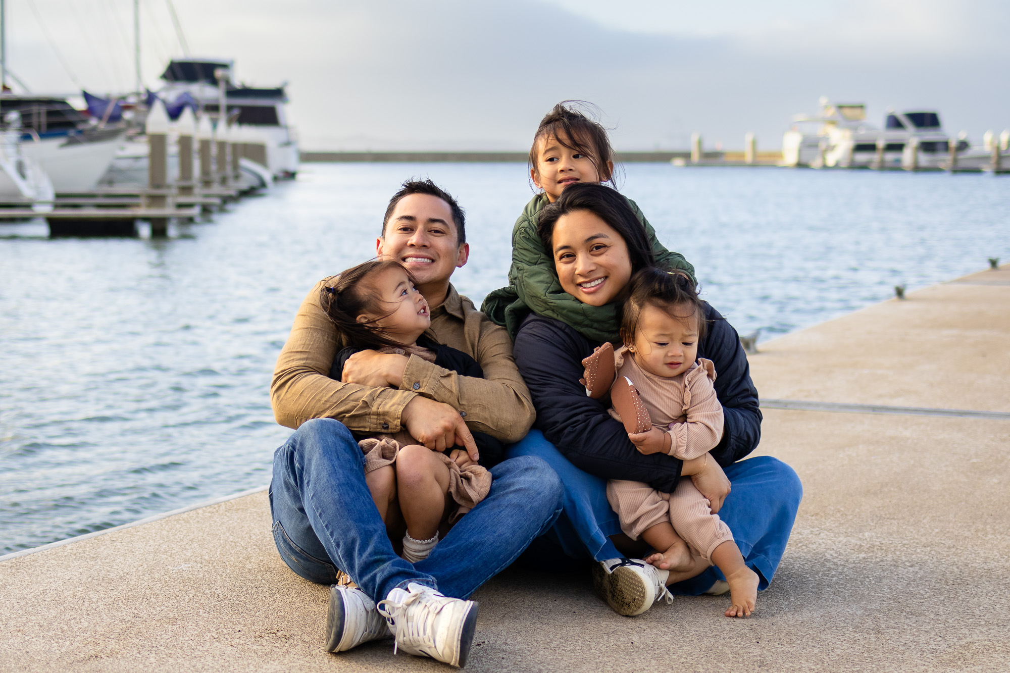 Family cuddling on a boat dock with Bay views at Oyster Point Marina