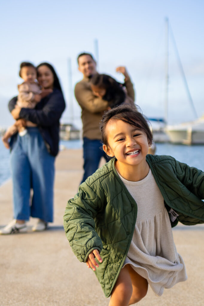 Toddler walking toward the dock with boats in the distance near Oyster Point Marina
