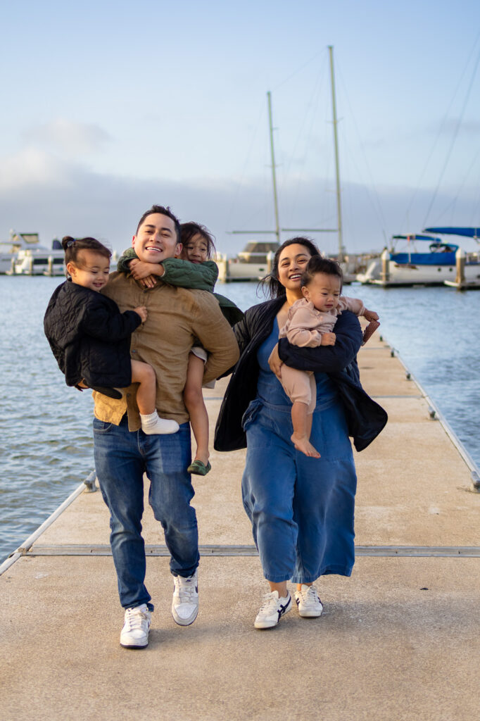 Sunset light on family walking through the boat dock with marina in the background at Oyster Point Marina