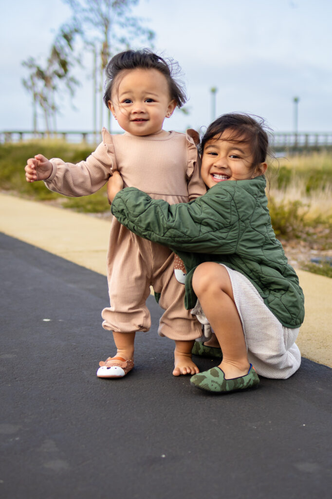Big sister hugging baby sibling on the paved Bay Trail in South San Francisco
