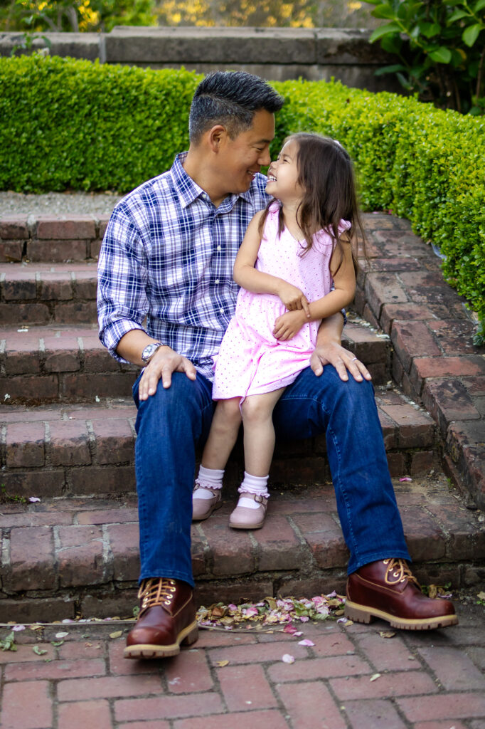 Girl and dad sitting on brick steps sharing a sweet nose-to-nose moment – What to Wear for Family Photoshoot