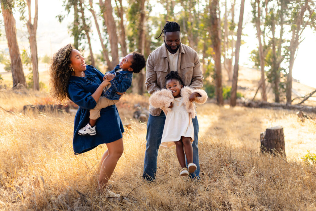 Parents swinging children playfully in the field – Ellobelle Photography