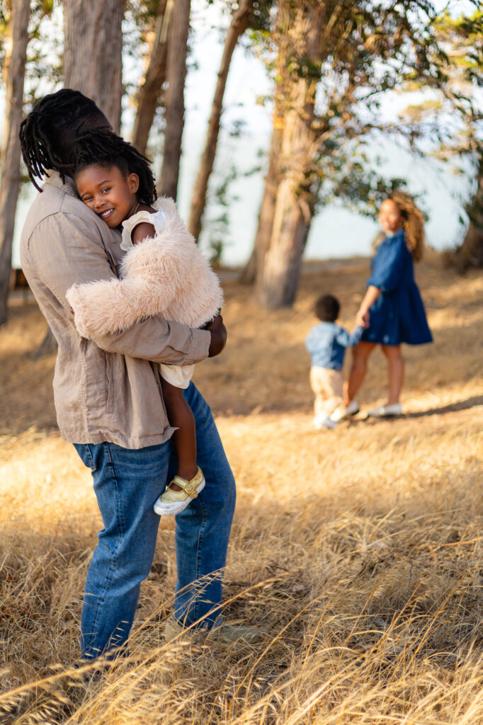 Father holding daughter while mother walks with son at Coyote Point – Ellobelle Photography
