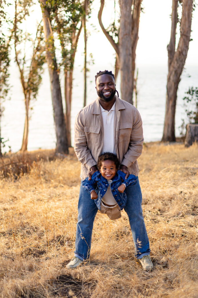 Father holding young son between his legs and smiling at Coyote Point – Ellobelle Photography