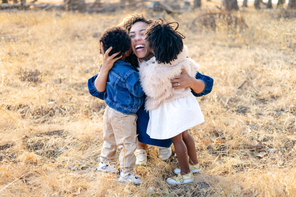 Mother laughing while hugging children outdoors at Coyote Point – Ellobelle Photography