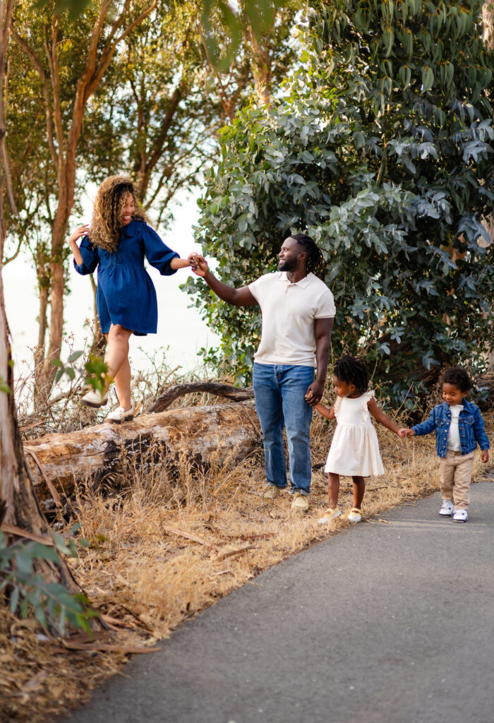 Family standing on a log holding hands – Ellobelle Photography