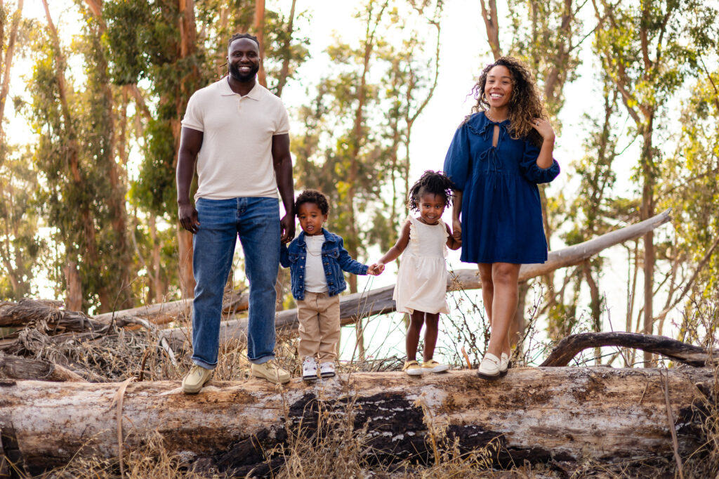 Family standing on a log holding hands at Coyote Point – Ellobelle Photography