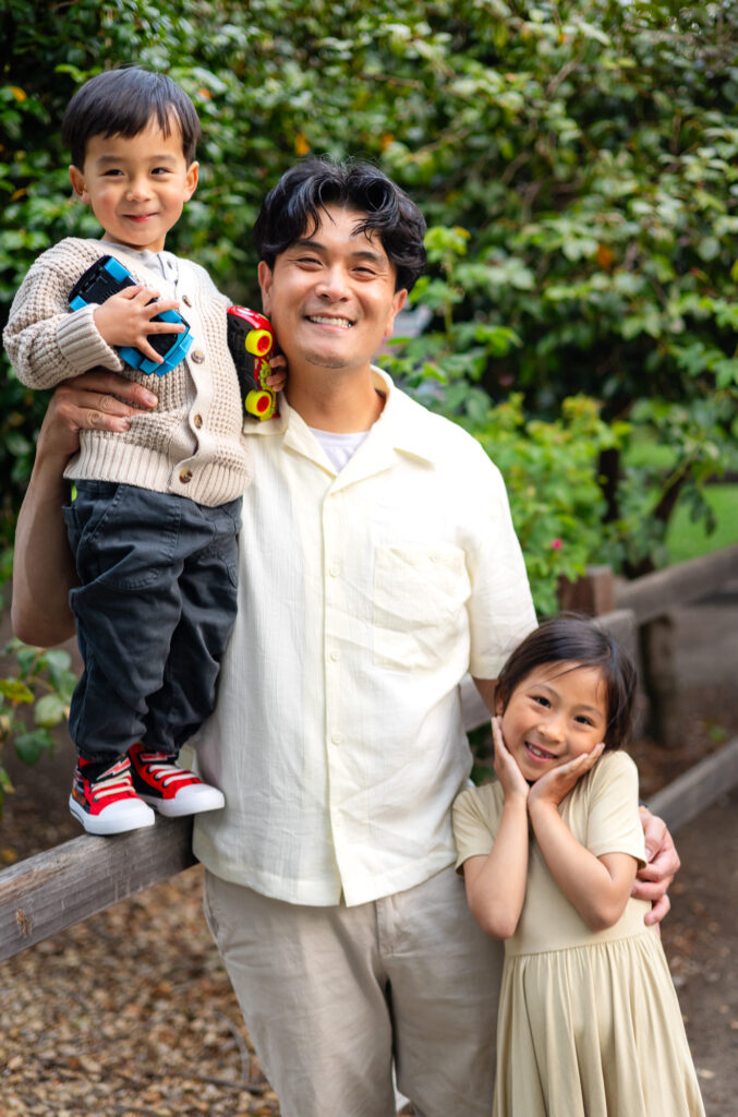 Father holding son and hugging daughter during Mini Sessions Photography - Ellobelle Photography in a garden setting.