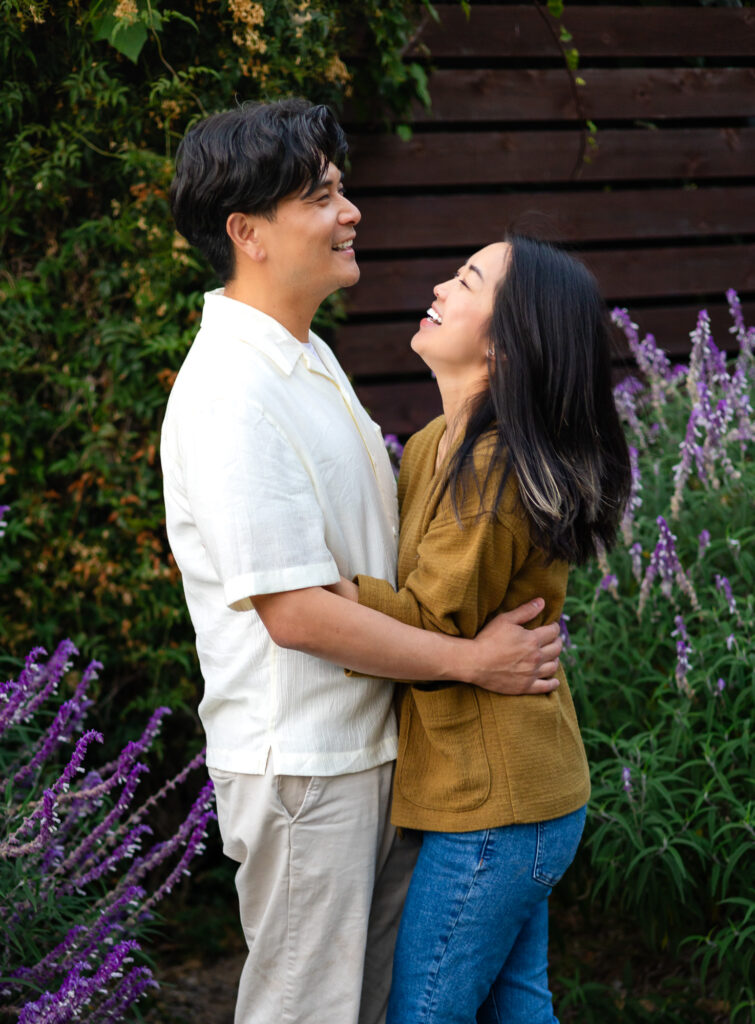Romantic couple laughing and holding each other in a natural garden setting for Mini Sessions Photography - Ellobelle Photography.