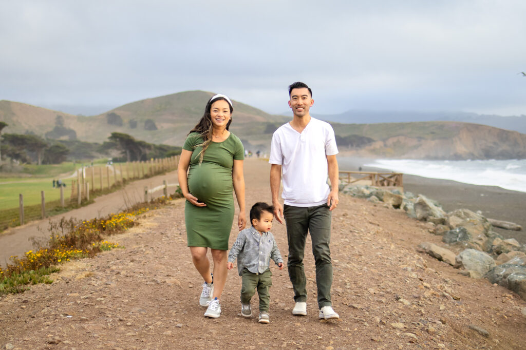 Family of three walking hand-in-hand on a beachside trail, celebrating new beginnings.