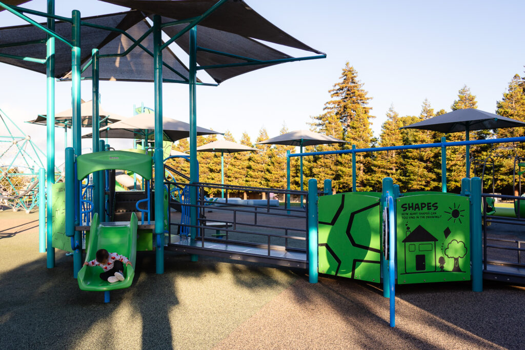 Child using a slide on inclusive playground structure at Millbrae Central Park – Ellobelle Photography