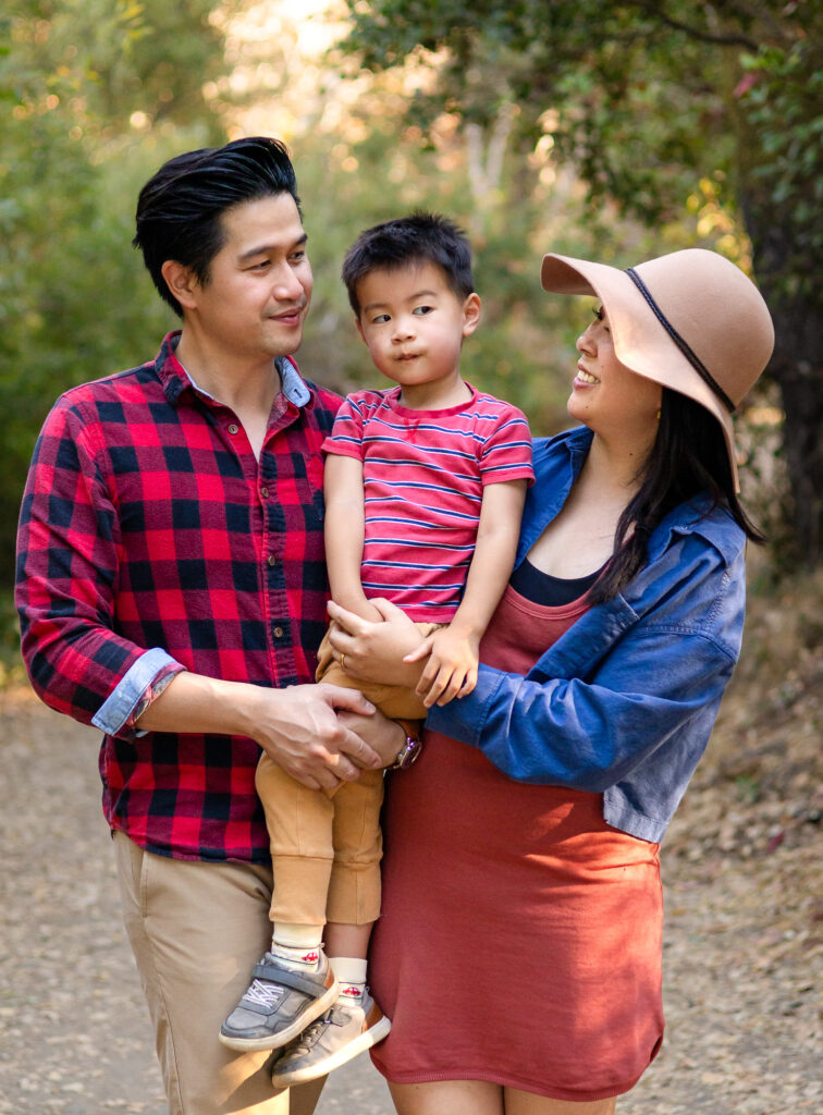 Parents holding child on trail during a neighborhood park family photoshoot