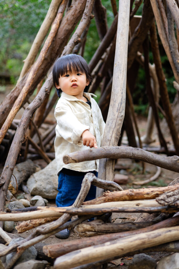 Child standing among tree branches at Redwood Grove Nature Preserve – Ellobelle Photography
