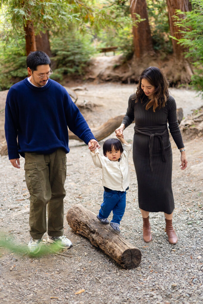 Child balancing on log with parents’ support at Redwood Grove Los Altos – Ellobelle Photography