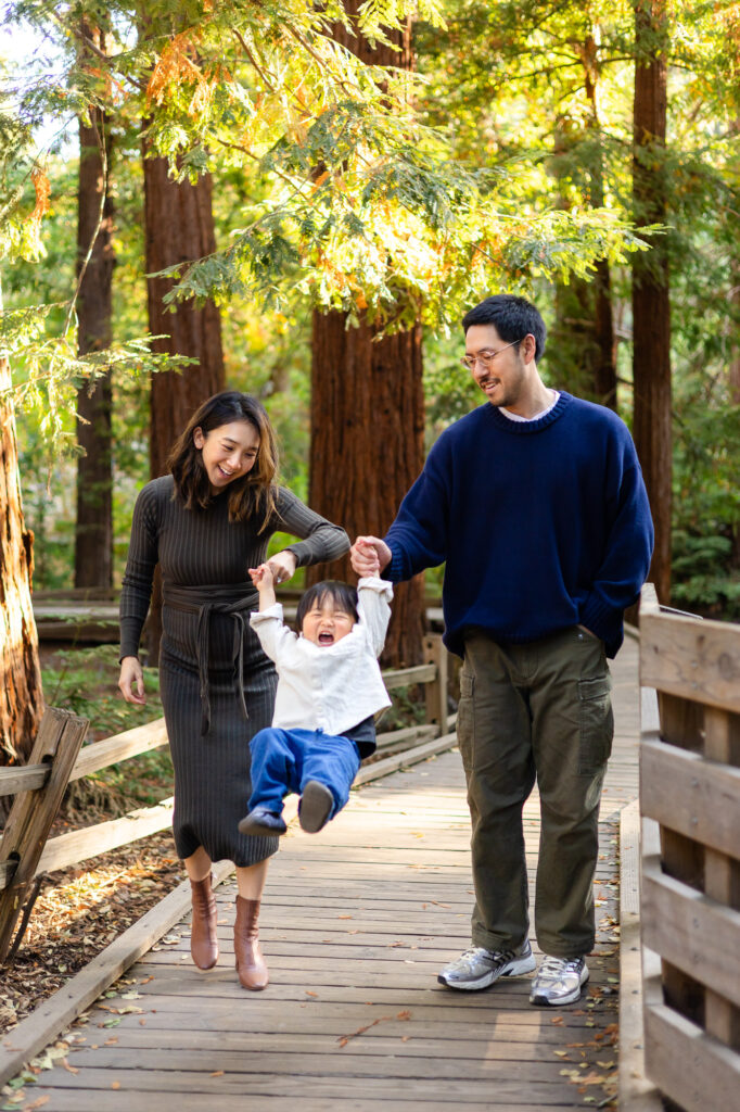 Parents swinging child along the wooden path at Redwood Grove Los Altos – Ellobelle Photography