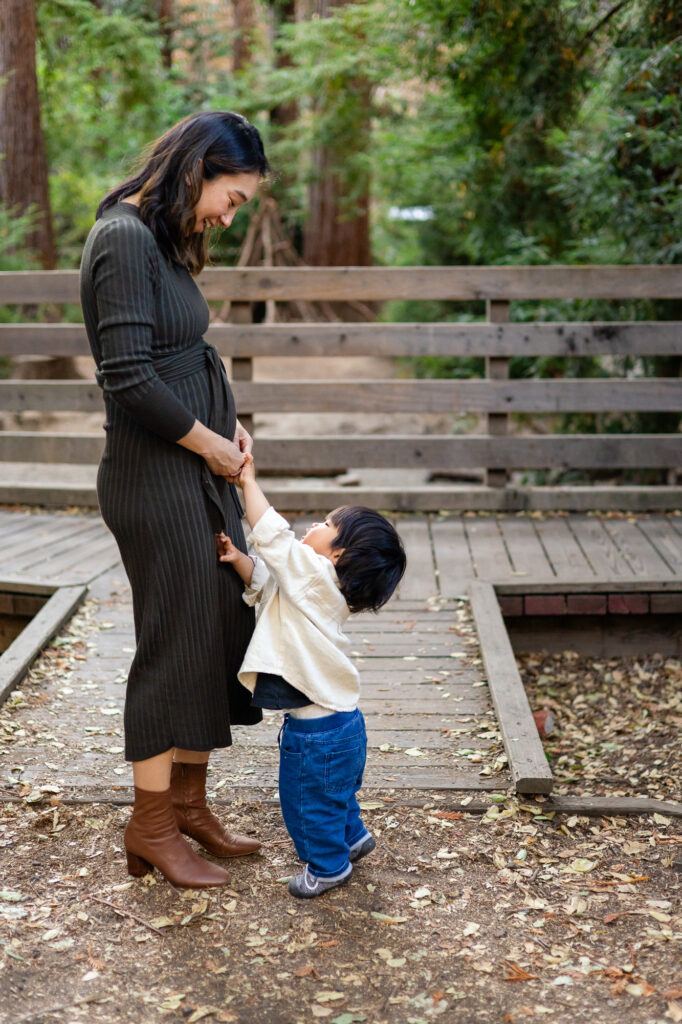 Sweet toddler holding mom’s belly during maternity session Redwood Grove Nature Preserve Los Altos photos Ellobelle Photography