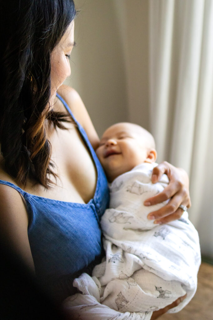 Smiling baby wrapped in swaddle cradled by mom – Ellobelle Photography San Francisco Newborn Photography
