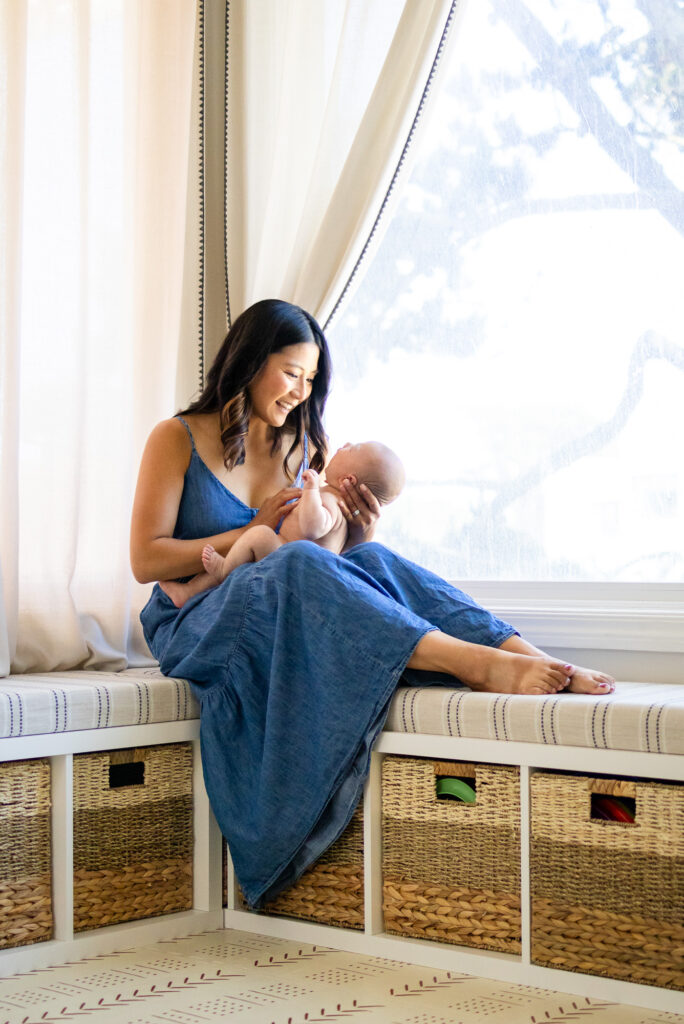 Mother in window seat cradling baby – San Francisco Newborn Photography by Ellobelle Photography