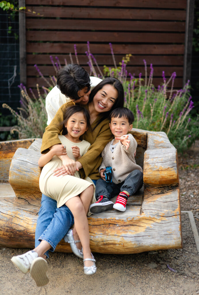 Family cuddling on a wooden bench at Washington Park Burlingame – Ellobelle Photography