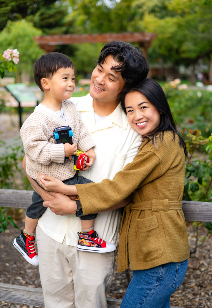 Family cuddling with young son holding toy cars at Washington Park – Ellobelle Photography