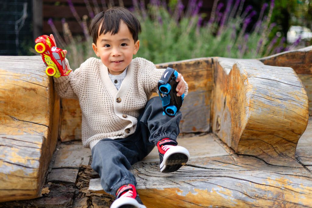 Toddler smiling with toy cars at Washington Park Burlingame – Ellobelle Photography