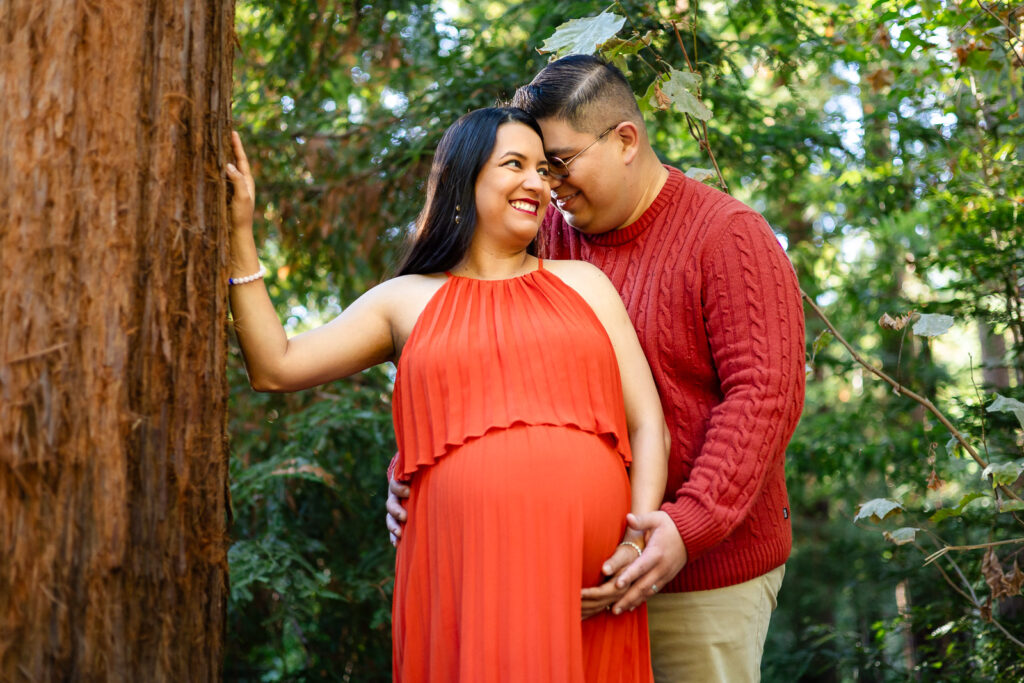 Couple embracing near redwood tree during maternity shoot