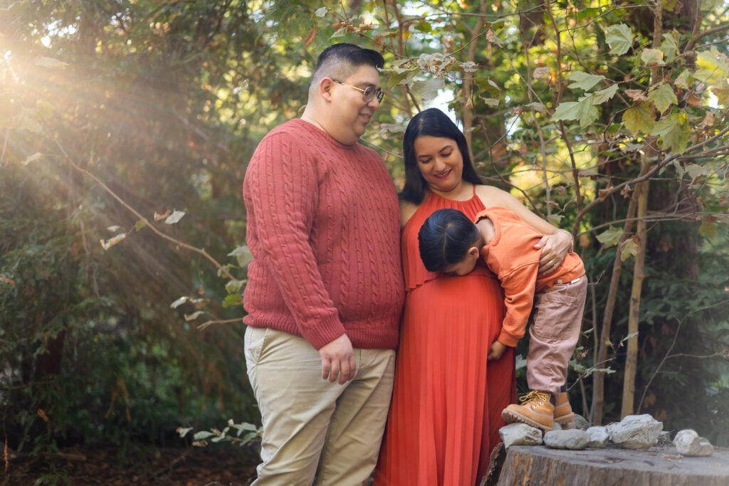 Son kissing mom’s baby bump on a tree stump during Bay Area family shoot