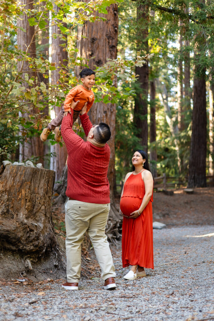 Dad lifting toddler as mom watches during forest maternity session in Bay Area – Ellobelle Photography