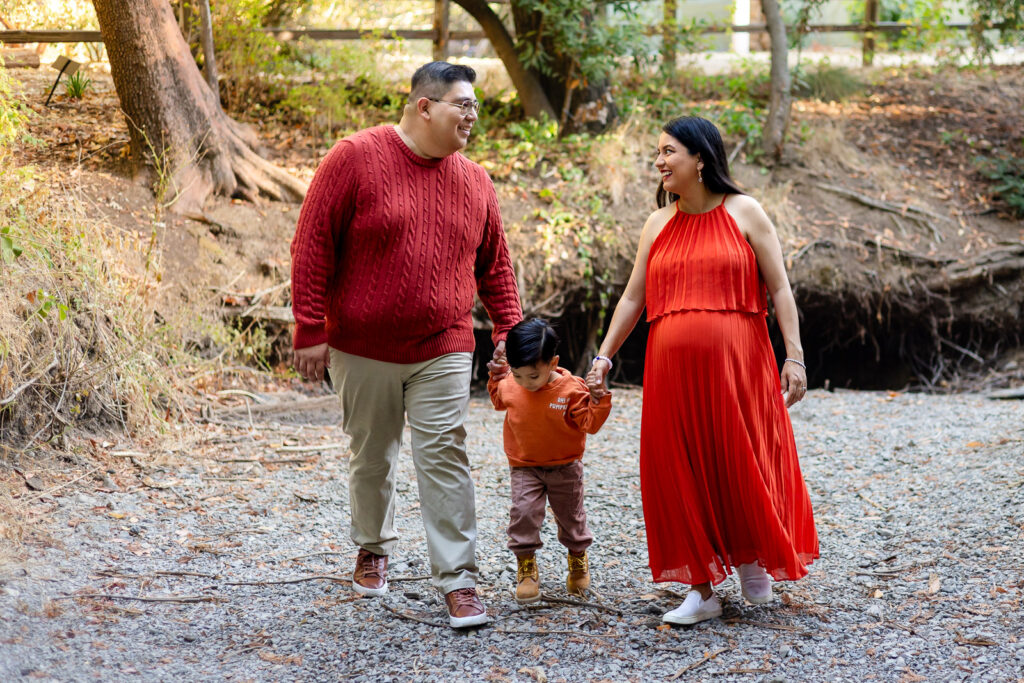 Family walking hand in hand on forest path during Bay Area maternity shoot – Ellobelle Photography